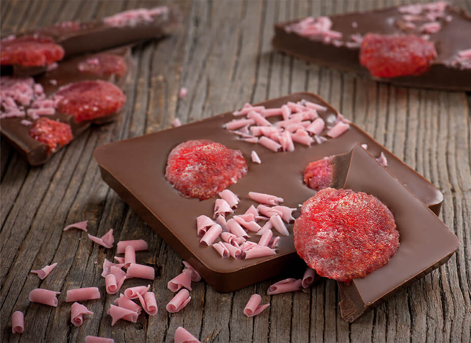 Laurence Tafelschokolade Signature Edition Vollmilchschokolade mit Erdbeeren fein angerichtet auf einer Teakholzunterlage Laurence Tafelschokolade Signature Edition Vollmilchschokolade mit Erdbeeren fein angerichtet auf einer Teakholzunterlage