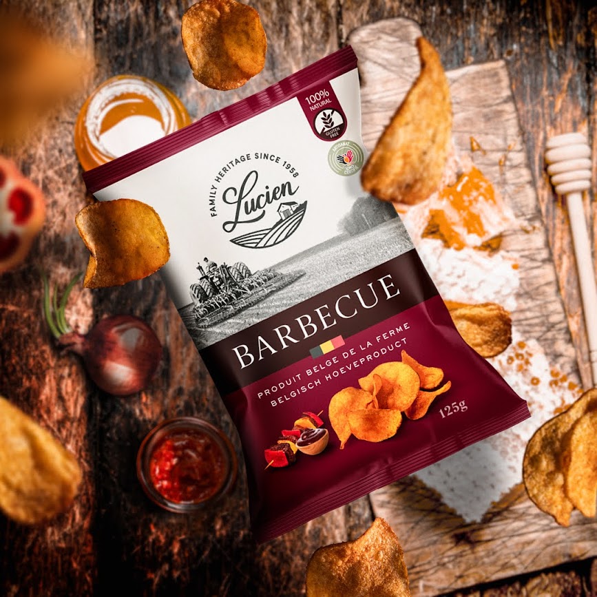 Lucien Chips BBQ Packung liegt auf einem Holzbrettchen, dass auf einem Holztisch liegt, direkt daneben steht eine Schale mit BBQ Sauce und eine Honigwabe, von oben fallen Chips herunter Lucien Chips BBQ Packung liegt auf einem Holzbrettchen, dass auf einem Holztisch liegt, direkt daneben steht eine Schale mit BBQ Sauce und eine Honigwabe, von oben fallen Chips herunter