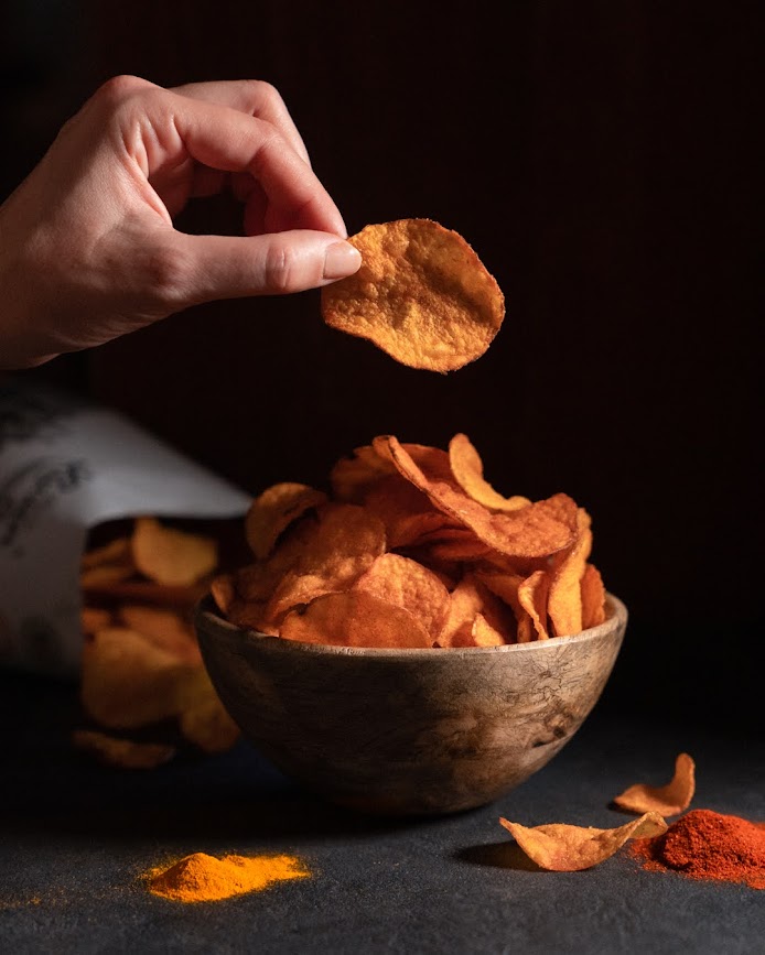 Chips in einer Schale, eine Hand die einen Chip zwischen zwei Fingern hält Chips in einer Schale, eine Hand die einen Chip zwischen zwei Fingern hält